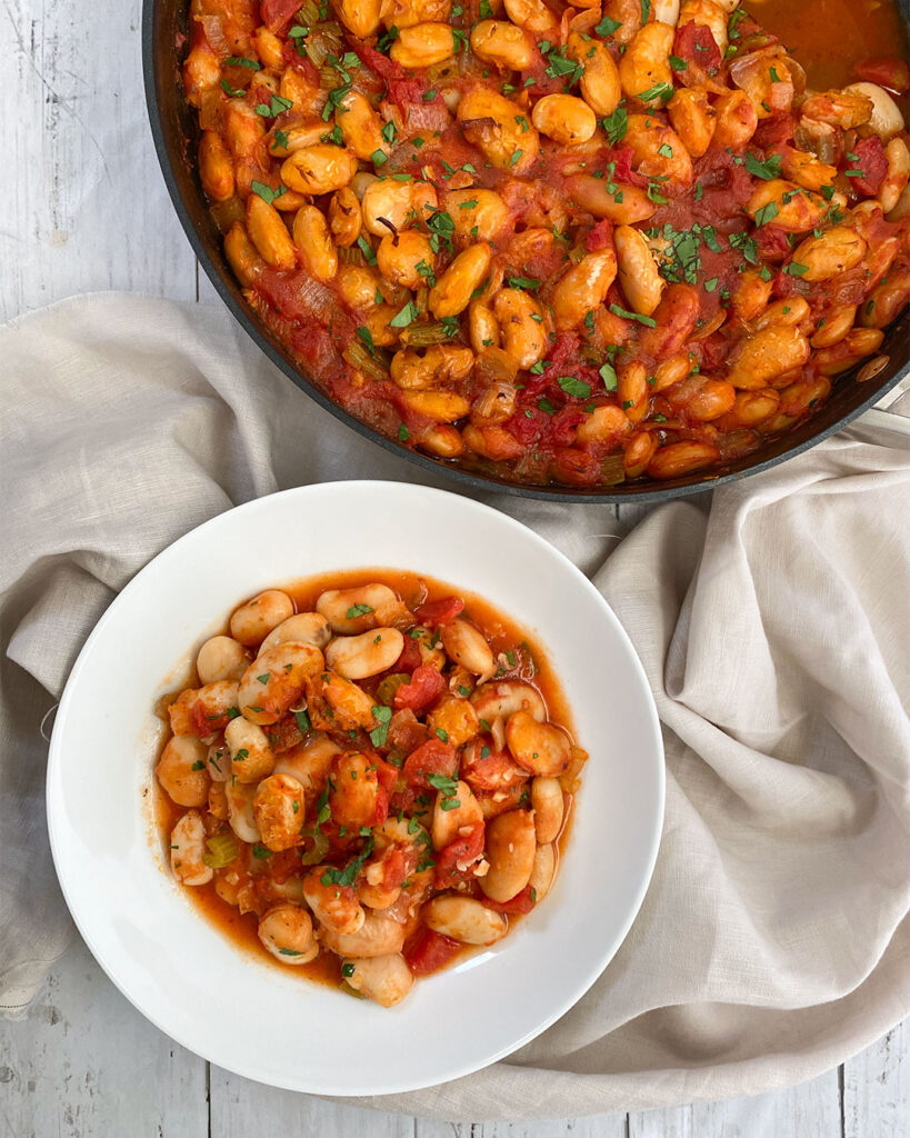 Greek Gigantes (Plaki) served in a bowl topped with a drizzle of olive oil!