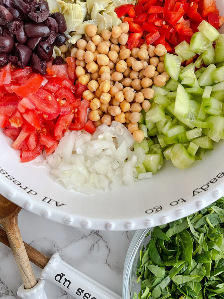 Chickpeas, olives, tomatoes, peppers, cucumbers, onions and artichokes in a bowl