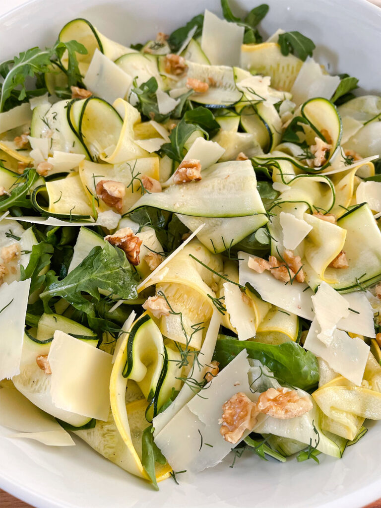 zucchini and squash ribbons on top of spinach and arugula with a lemon vinagarette