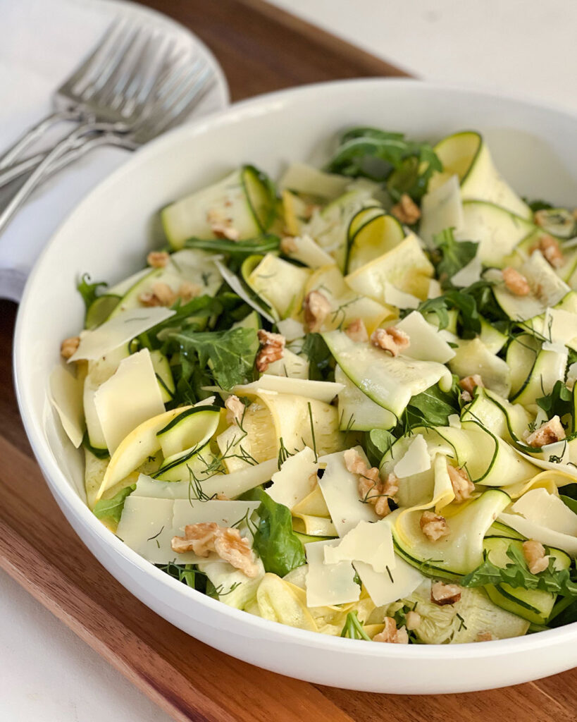 Ribbons of zucchini and yellow squash on top of greens with shaved parmesan 