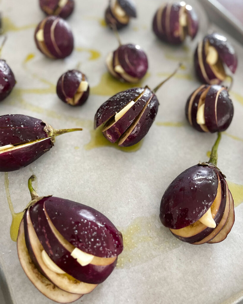 Eggplant sliced with garlic on a baking dish.