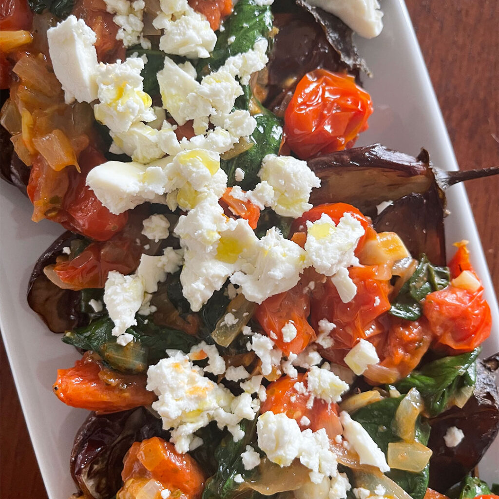 Roasted eggplant topped with sautéed vegetables and feta cheese