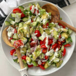 A bowl of salad with tomatoes, cucumber, and avocados drizzled with a creamy feta dressing.