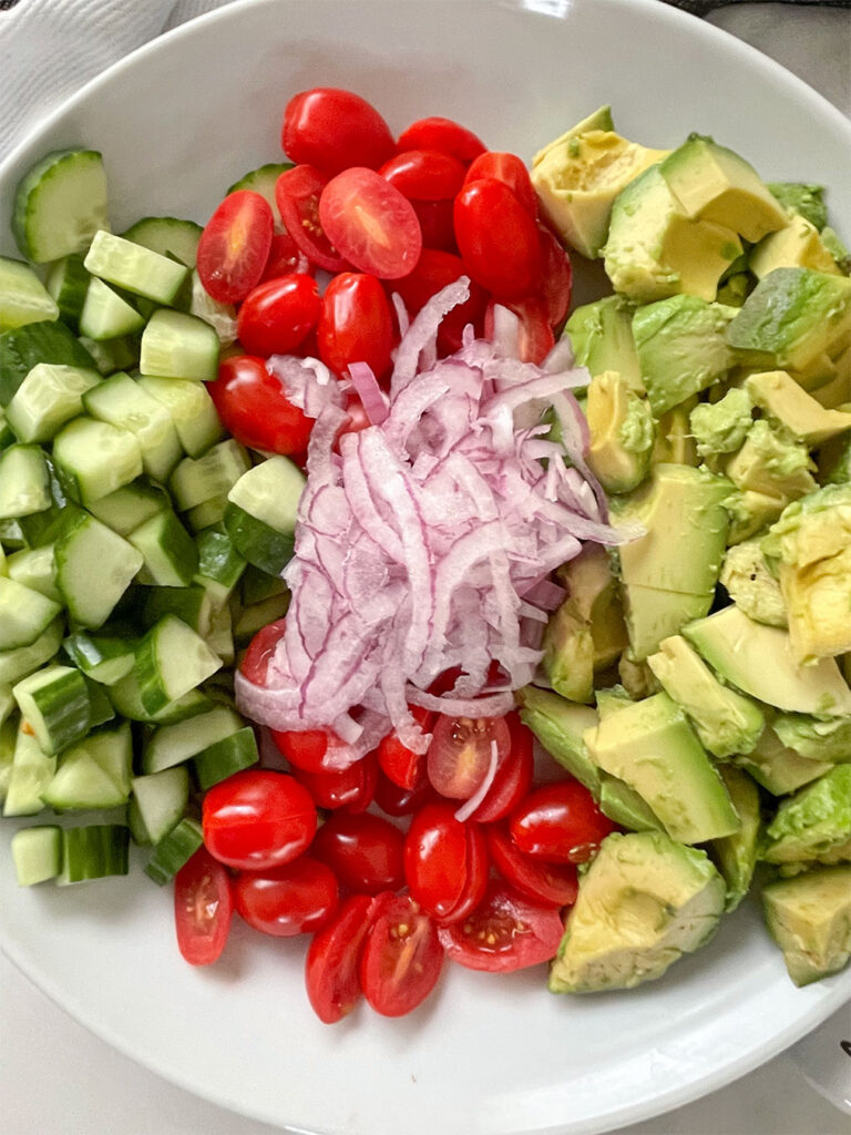 A picture of the salad with red juicy tomatoes, crisp cucumbers, creamy avocado and sweet red onion.