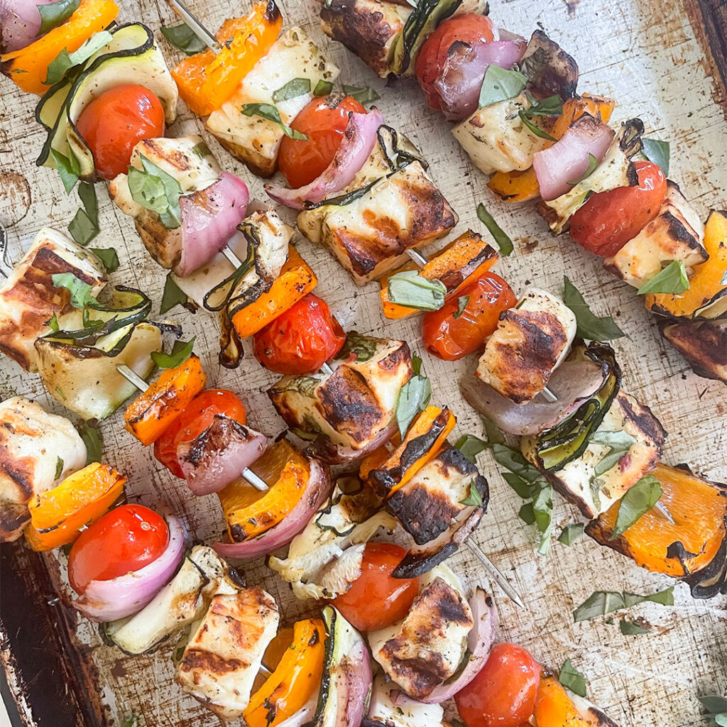 Sizzling and delectable Grilled Halloumi Skewers, featuring charred edges of Halloumi cheese, vibrant peppers, zucchini ribbons, and cherry tomatoes, bursting with irresistible flavors.