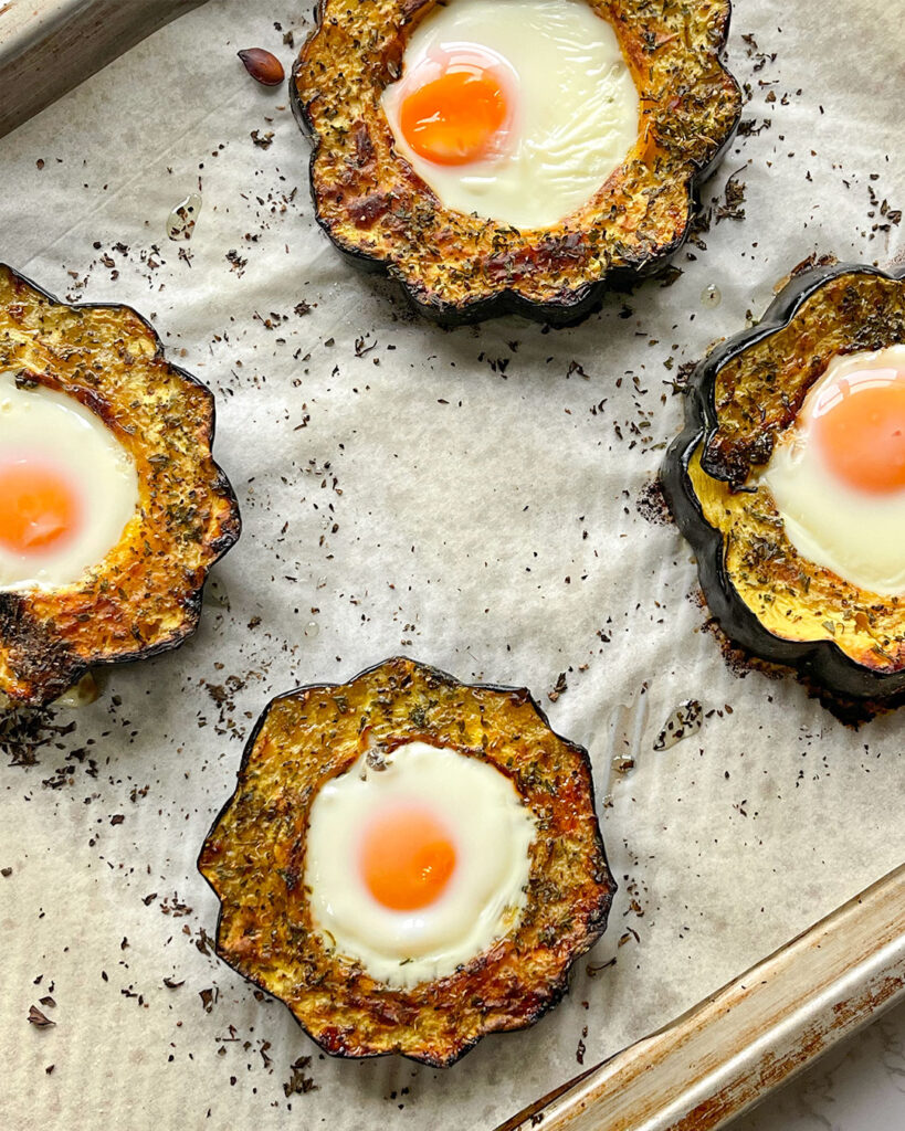 Baked acorn squash with an egg in the middle on a sheet pan.