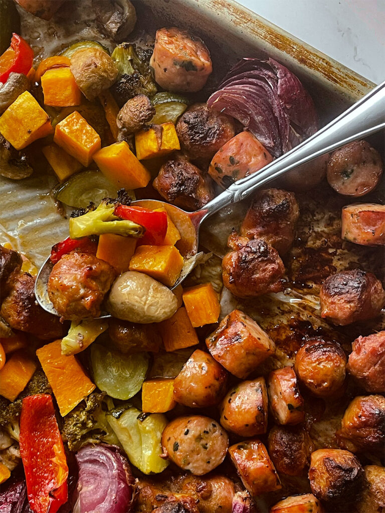 Spoon on the sheet pan with the cooked sausage and vegetables